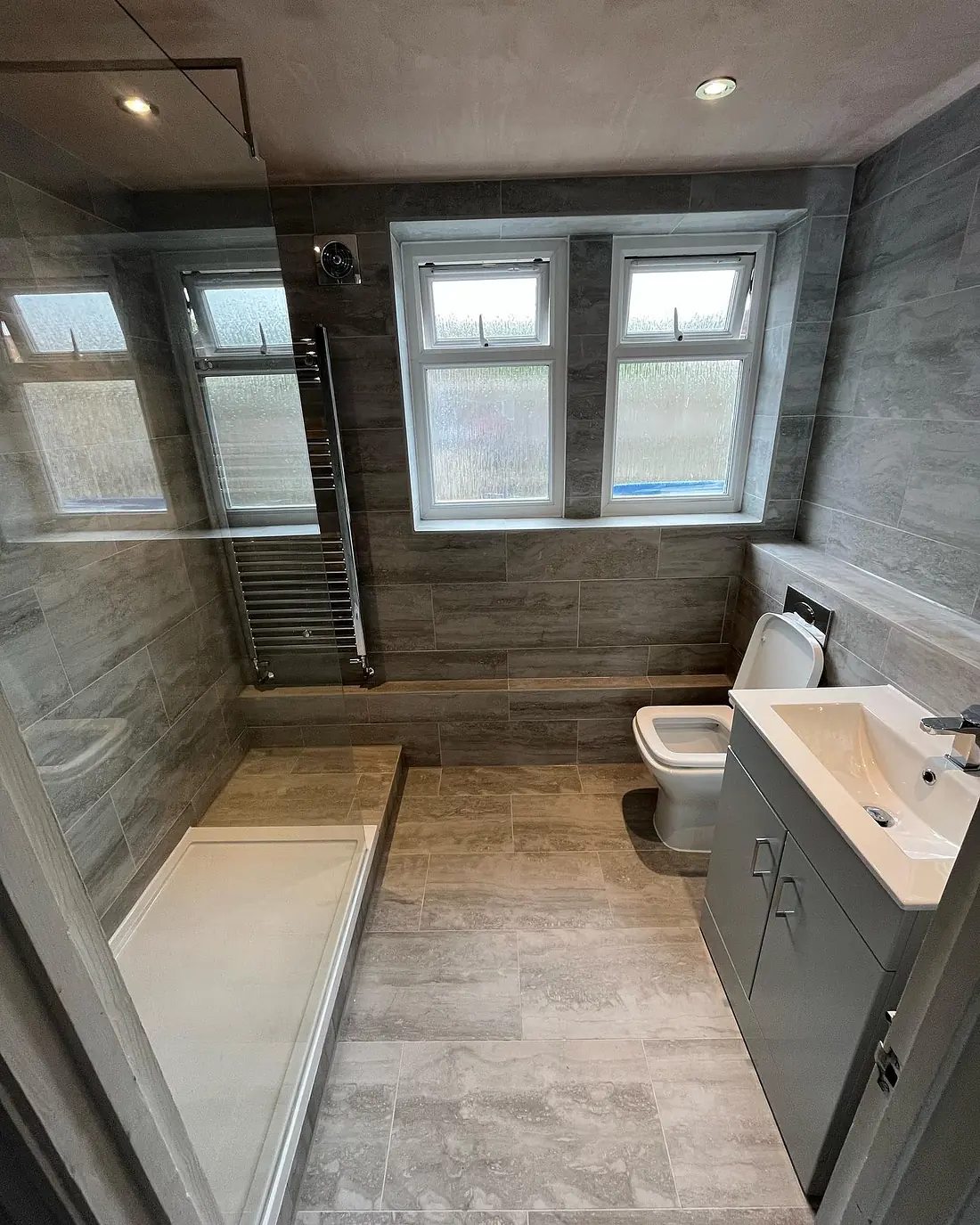 Grey stone-effect bathroom with a walk-in shower, a chrome towel rail and a vanity unit