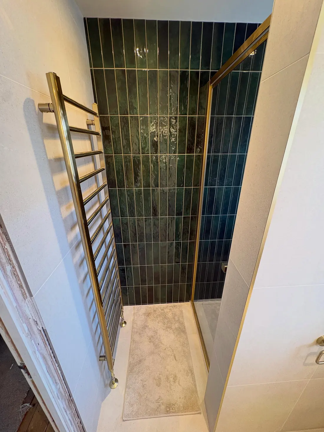 Dark green tiled shower with a brushed brass frame and a brass towel rail in Kennington