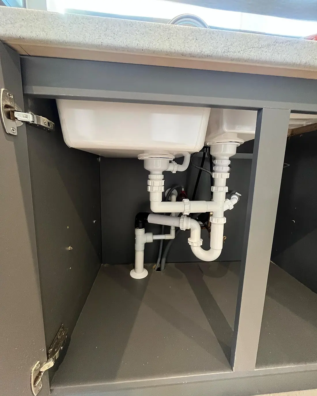 Neat white waste pipework beneath a kitchen sink