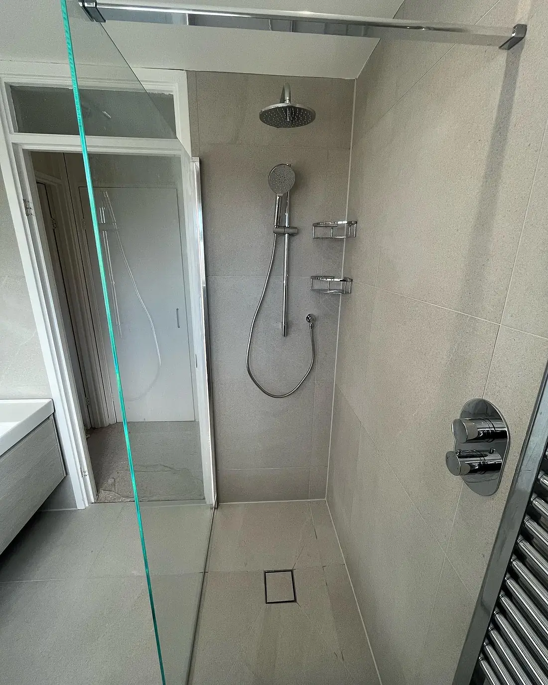 Walk-in wet-room shower with a glass screen and a linear drain