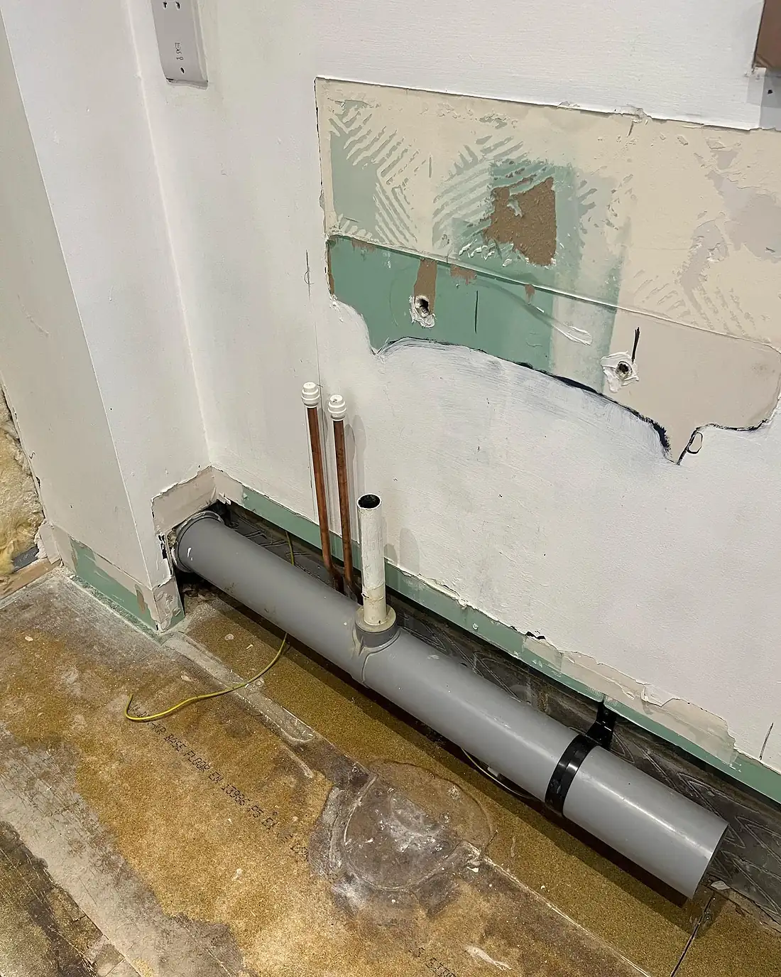 The old en-suite taken back to bare walls and floor, with waste and supply pipework exposed