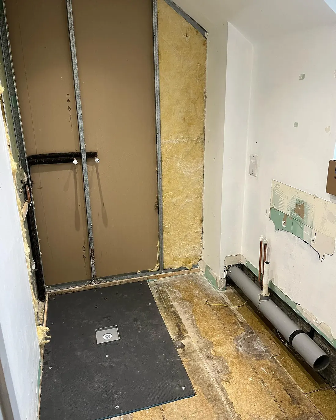 A new wet-room tray in place with the wall cavity boarded around it