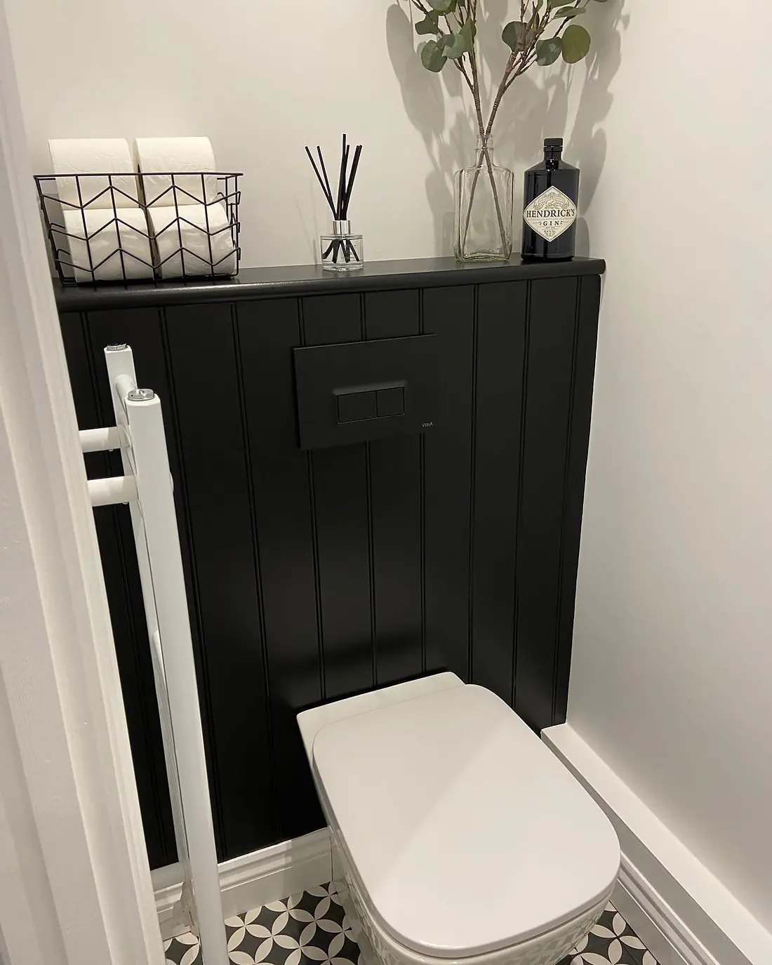 Cloakroom with black panelling behind the toilet and a black-and-white patterned floor